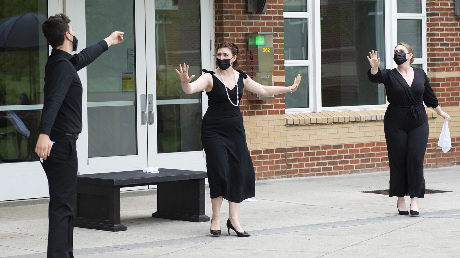  Three opera students performing outside dressed in all black.