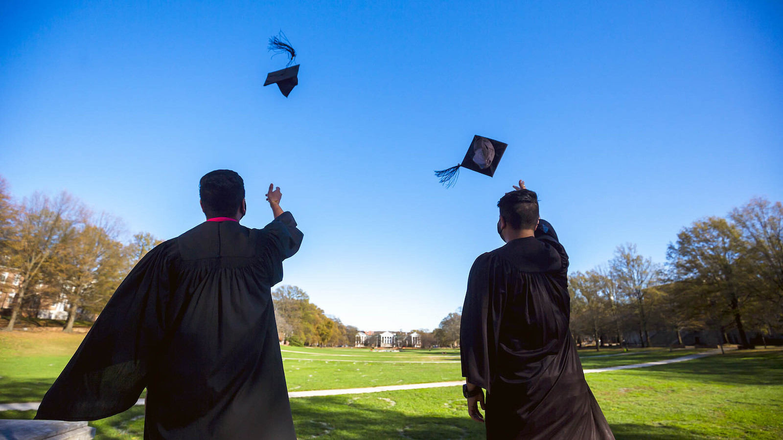 2 graduating students throw their caps in the air