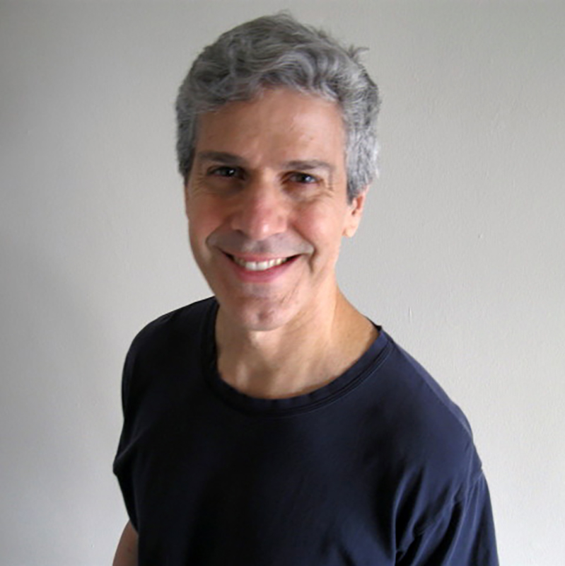 Headshot of Fernando Rios. He is wearing a black t-shirt and is photographed against a grey back drop
