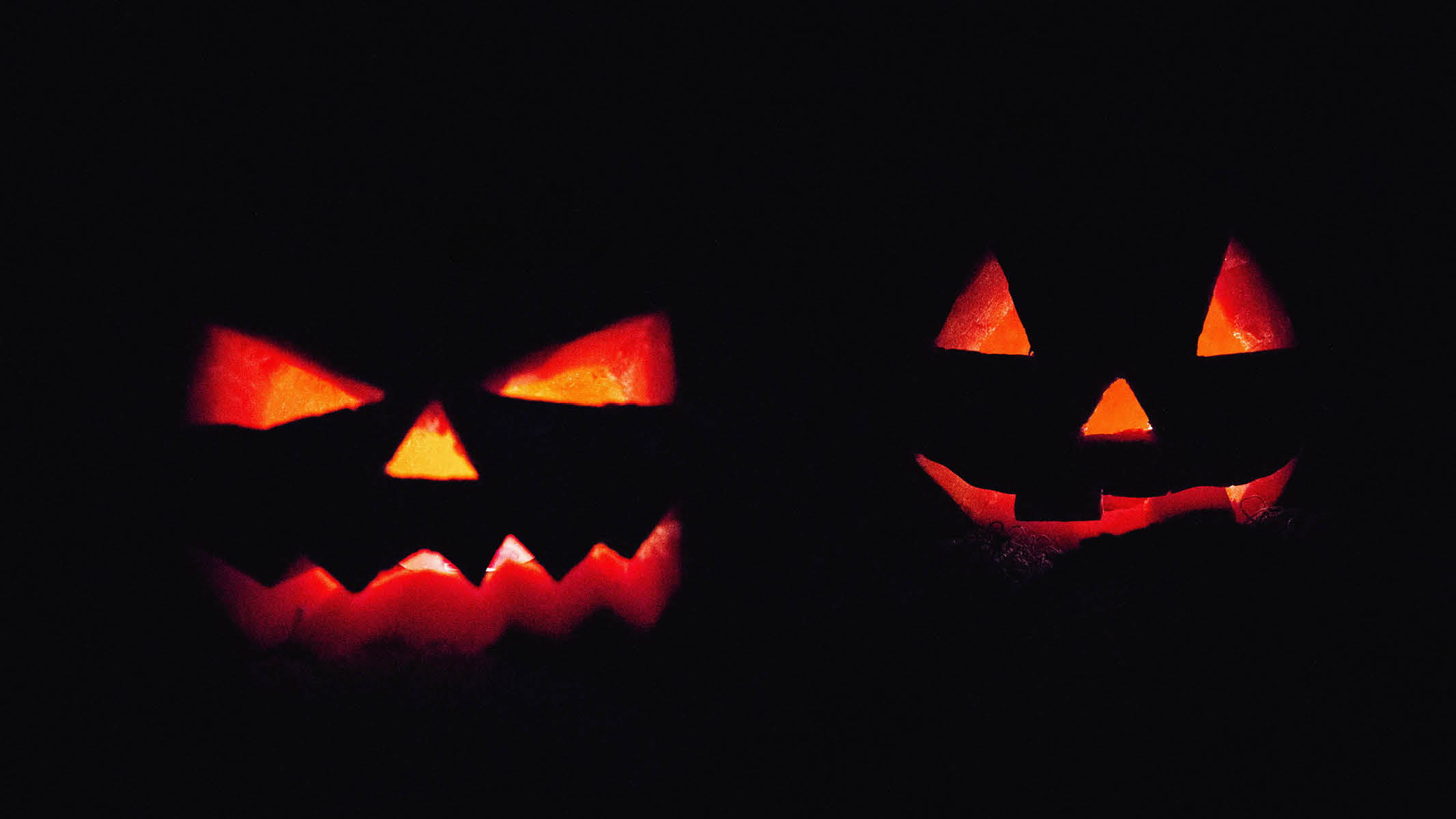 Two pumpkins with scary faces carved in for Halloween.